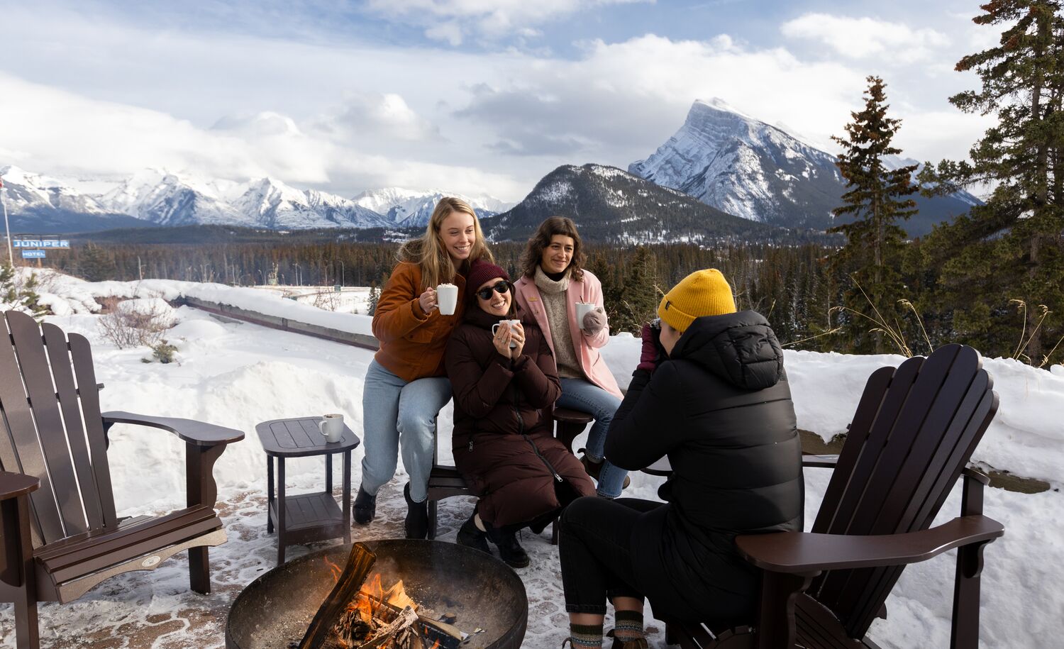 Friends enjoy a hot chocolate outside at the Juniper Bistro with Mount Rundle in the background in Banff National Park.